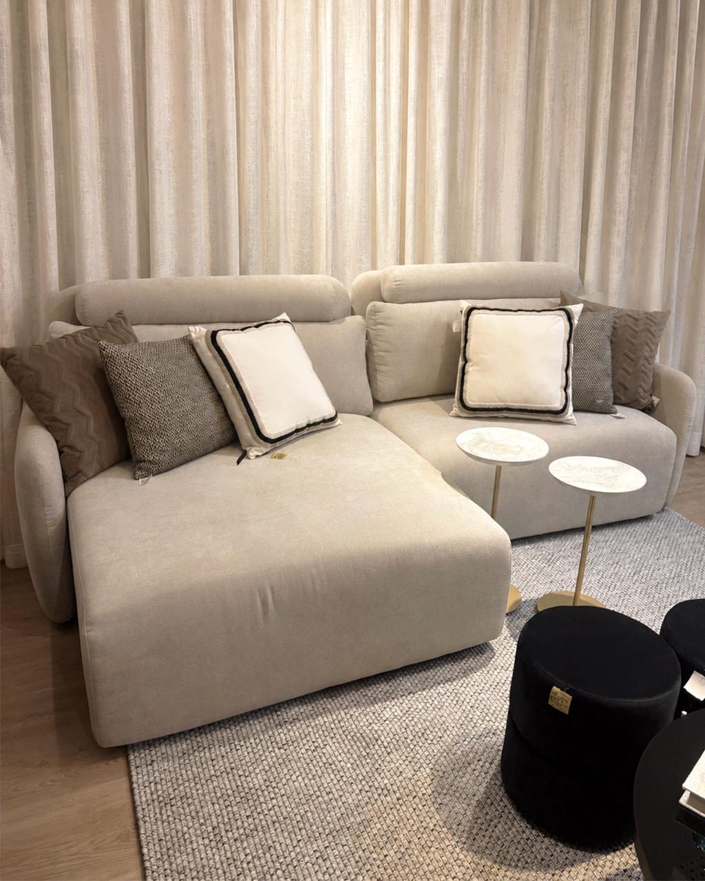 Living contemporâneo com sofá modular claro, almofadas decorativas e mesas laterais em mármore
